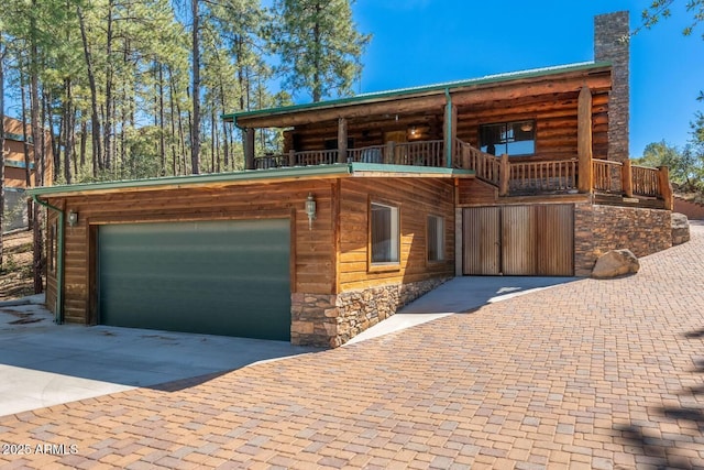 view of front facade with concrete driveway, stone siding, a garage, and a chimney