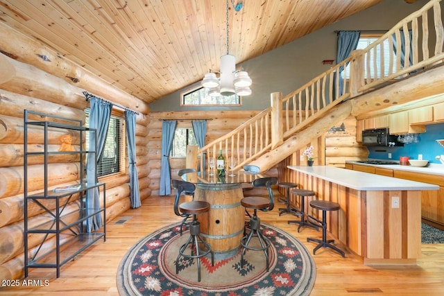 dining area with log walls, light wood-style floors, and stairway