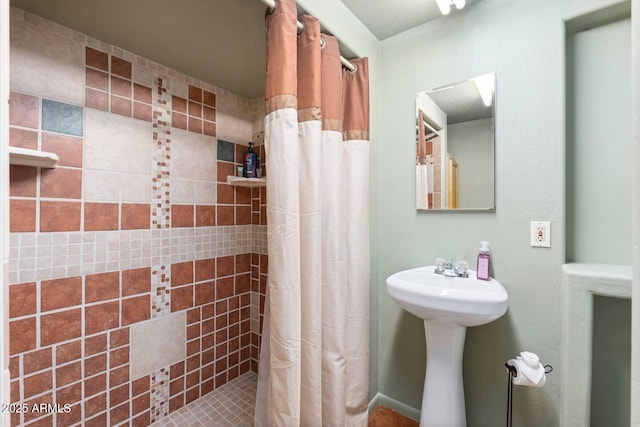 bathroom featuring a tile shower and a sink