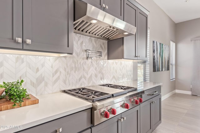 kitchen featuring ventilation hood, gray cabinets, backsplash, and stainless steel gas stovetop