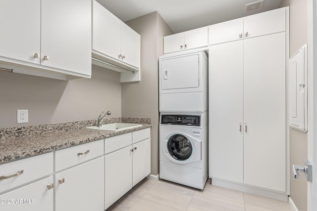 washroom with stacked washer and dryer, sink, and cabinets