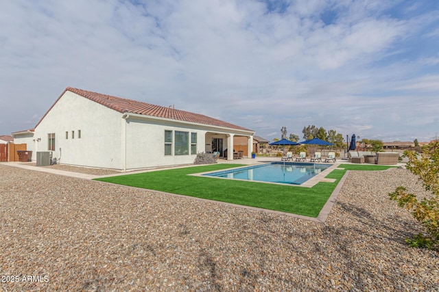 view of pool with cooling unit, a patio area, and a lawn