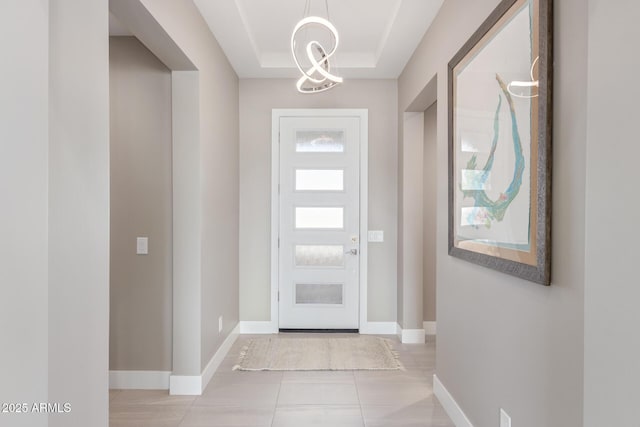 tiled entrance foyer with an inviting chandelier and a tray ceiling