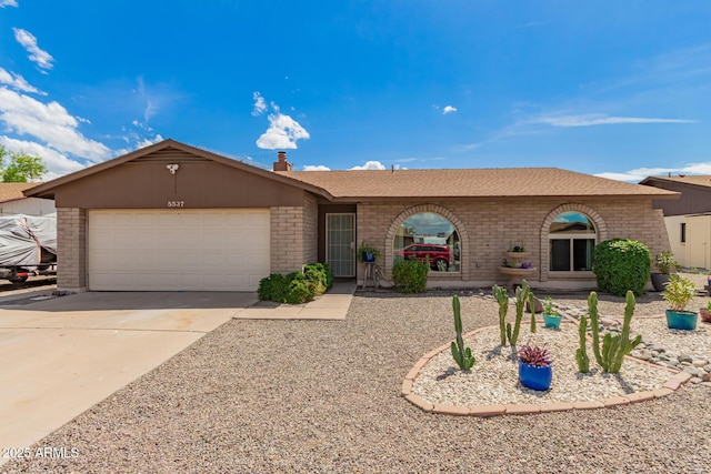 ranch-style home with a chimney, a garage, concrete driveway, and brick siding