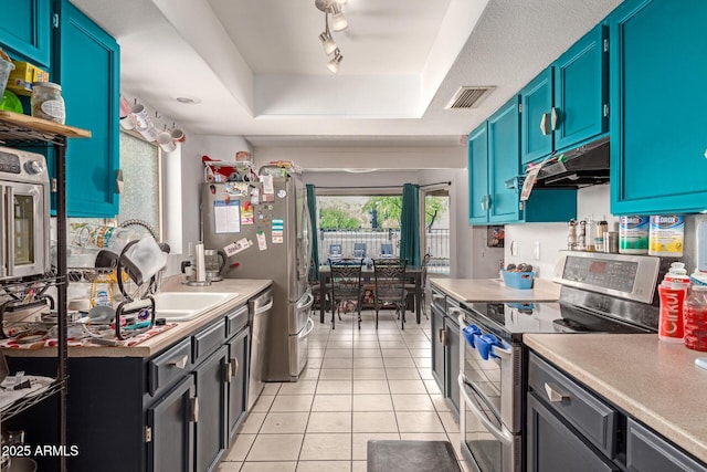 kitchen with light tile patterned floors, visible vents, under cabinet range hood, stainless steel appliances, and a raised ceiling