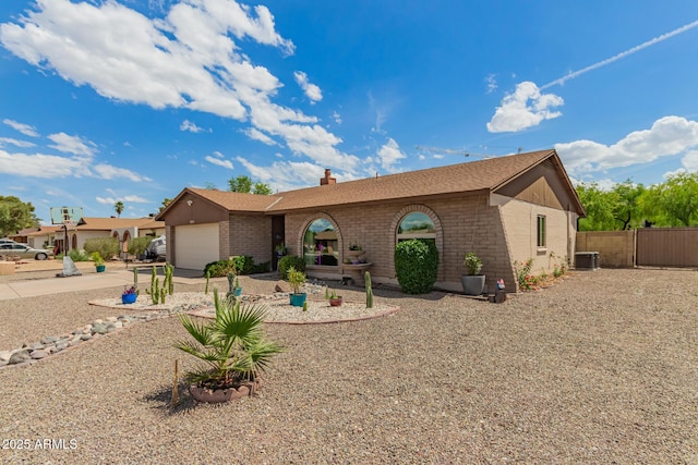 ranch-style house featuring central air condition unit, a chimney, a garage, and brick siding