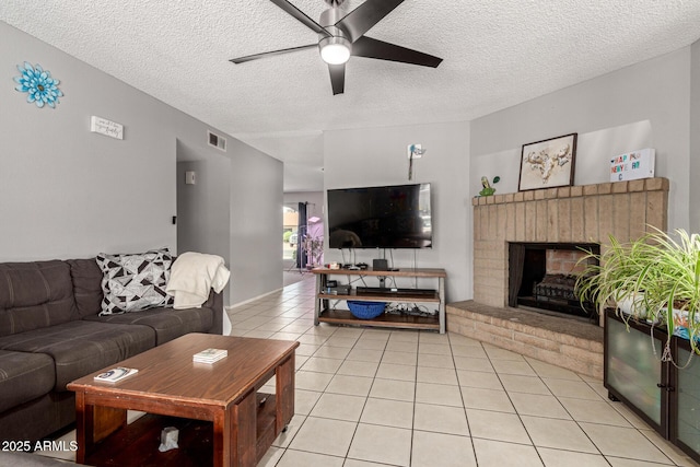 living room featuring visible vents, ceiling fan, light tile patterned flooring, and a textured ceiling