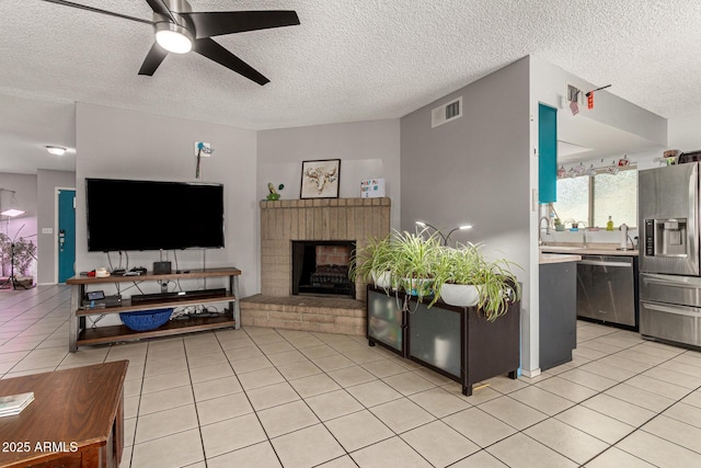 living area featuring ceiling fan, a textured ceiling, visible vents, and light tile patterned flooring