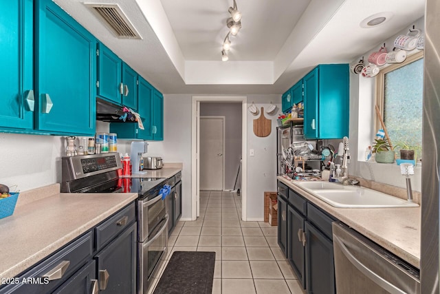 kitchen with light tile patterned floors, under cabinet range hood, visible vents, a raised ceiling, and stainless steel appliances