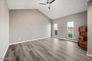spare room with baseboards, ceiling fan, vaulted ceiling, and wood finished floors