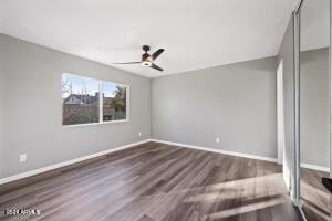 unfurnished bedroom with baseboards, a ceiling fan, and dark wood finished floors