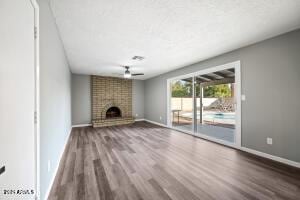 unfurnished living room with baseboards, wood finished floors, and a fireplace