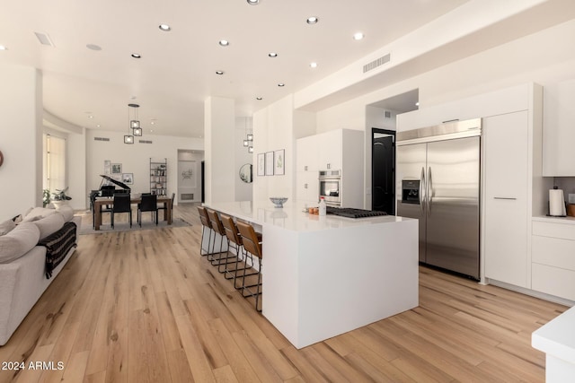 kitchen featuring appliances with stainless steel finishes, a breakfast bar, light hardwood / wood-style floors, and white cabinets