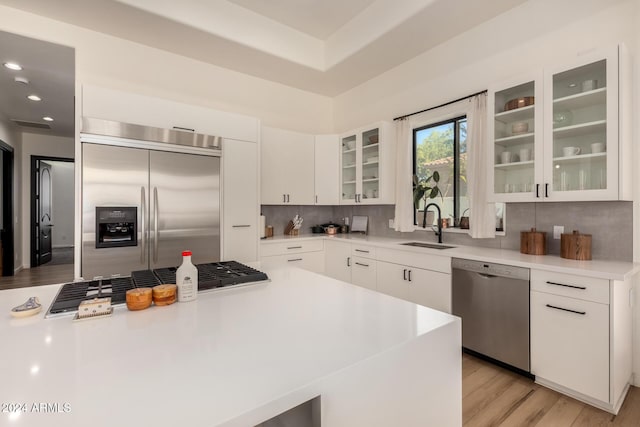 kitchen featuring sink, light hardwood / wood-style flooring, backsplash, stainless steel appliances, and white cabinets