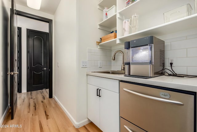 kitchen with sink, white cabinets, decorative backsplash, stainless steel dishwasher, and light hardwood / wood-style flooring