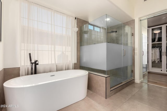 bathroom with shower with separate bathtub and tile walls