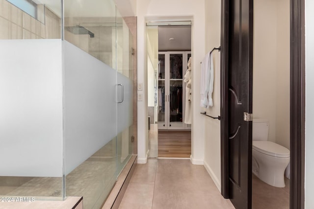 bathroom with tile patterned floors, toilet, and an enclosed shower