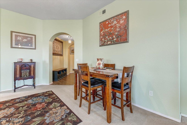 dining area with a textured ceiling and carpet flooring