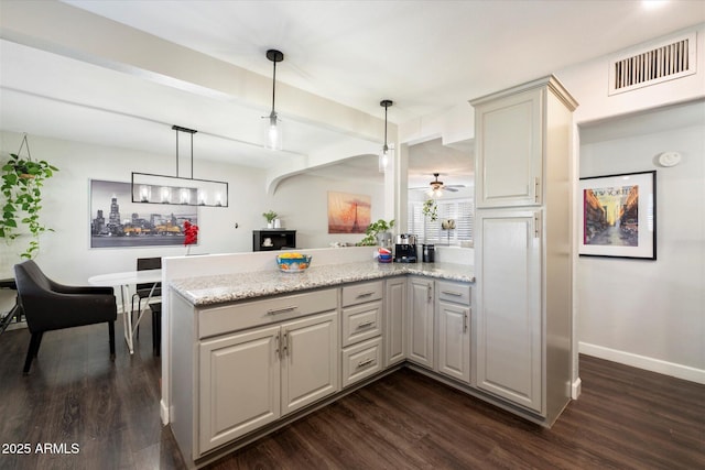 kitchen with light stone countertops, dark hardwood / wood-style flooring, decorative light fixtures, and kitchen peninsula