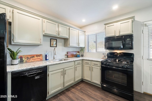 kitchen featuring black appliances, dark hardwood / wood-style flooring, light stone counters, and sink