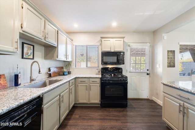 kitchen featuring light stone countertops, black appliances, dark hardwood / wood-style flooring, and sink