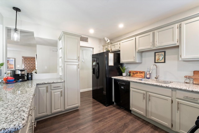 kitchen featuring sink, light stone countertops, black appliances, and dark wood-type flooring