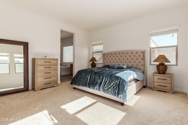 bedroom featuring light colored carpet and ensuite bathroom