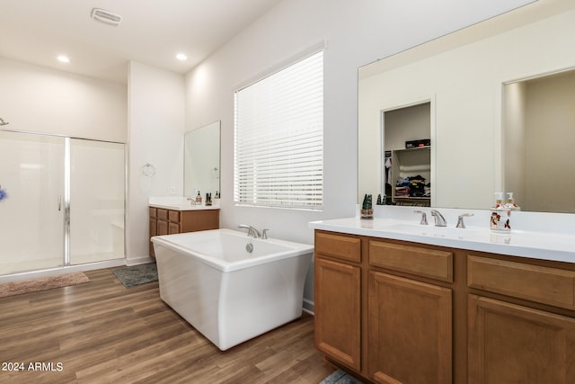 bathroom featuring hardwood / wood-style floors, plus walk in shower, and vanity