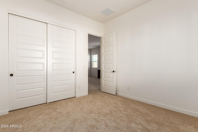 unfurnished bedroom with a closet and light colored carpet