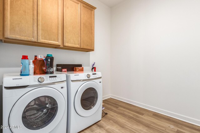 washroom featuring washer and dryer, cabinets, and light hardwood / wood-style floors