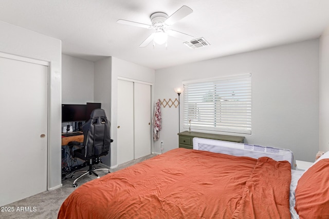 bedroom featuring visible vents, carpet flooring, two closets, and a ceiling fan