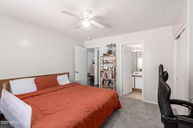 bedroom with connected bathroom, light colored carpet, and a ceiling fan