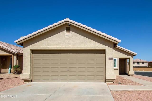 view of front of home with stucco siding, a garage, driveway, and a tile roof