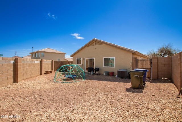 back of property with stucco siding, central AC, and a fenced backyard