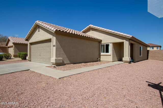 exterior space with fence, stucco siding, concrete driveway, a garage, and a tiled roof