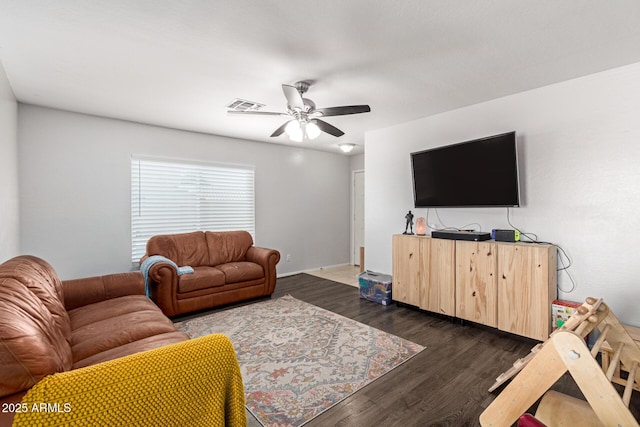 living area with dark wood-type flooring, a ceiling fan, visible vents, and baseboards