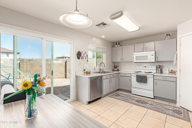 kitchen featuring visible vents, light tile patterned floors, gray cabinets, white appliances, and a sink