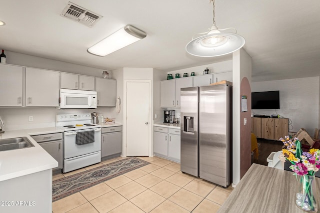 kitchen featuring visible vents, a sink, white appliances, light countertops, and light tile patterned floors