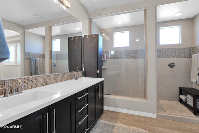 bathroom with vanity, plenty of natural light, a tile shower, and decorative backsplash