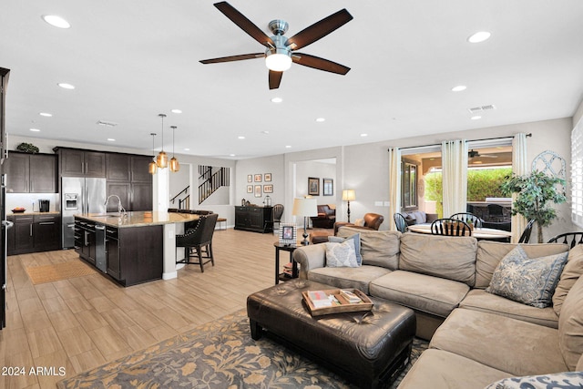 living room with ceiling fan, light hardwood / wood-style flooring, and sink