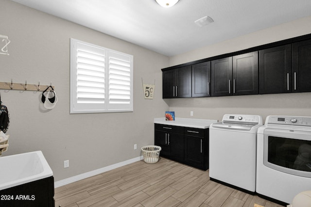 laundry room with cabinets, separate washer and dryer, and light wood-type flooring