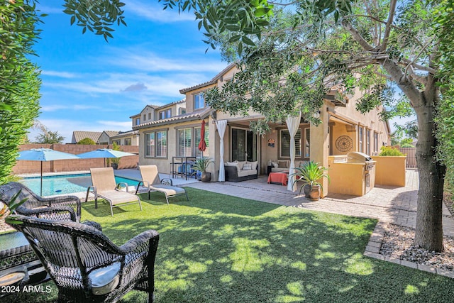 rear view of house featuring a fenced in pool, a yard, a patio, and exterior kitchen