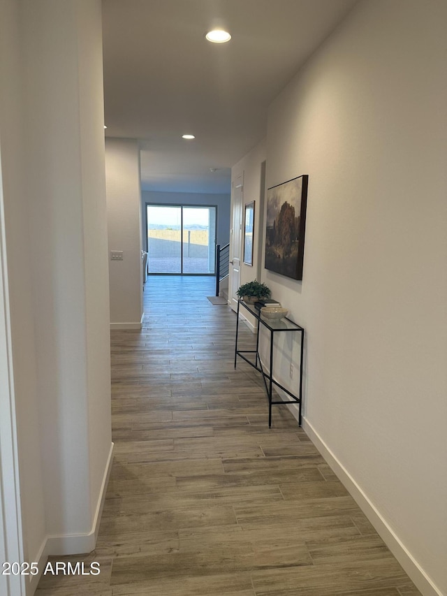 corridor featuring recessed lighting, wood finished floors, and baseboards