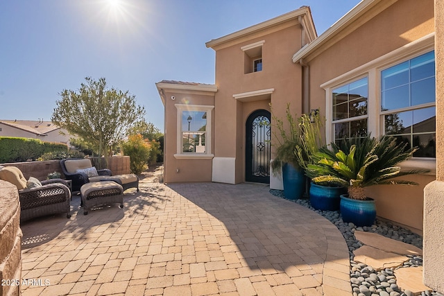 view of exterior entry featuring an outdoor living space and a patio area