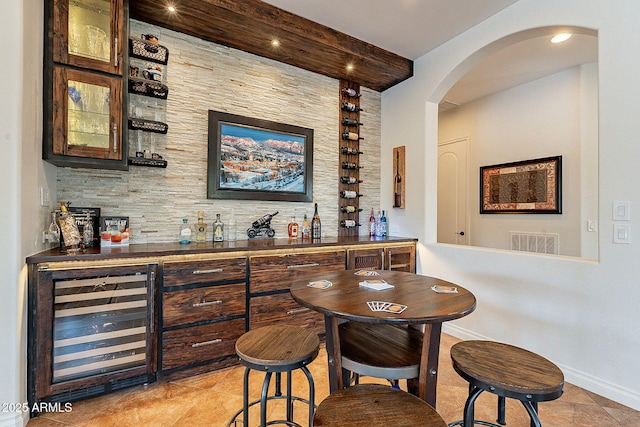 bar with dark brown cabinets and wine cooler