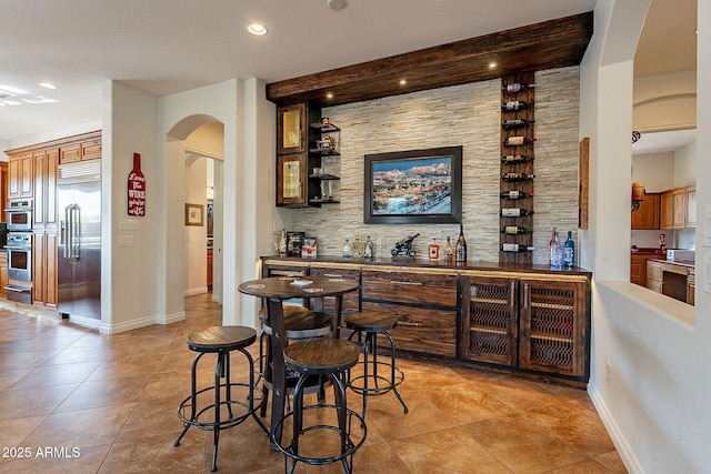 bar with light tile patterned flooring and appliances with stainless steel finishes