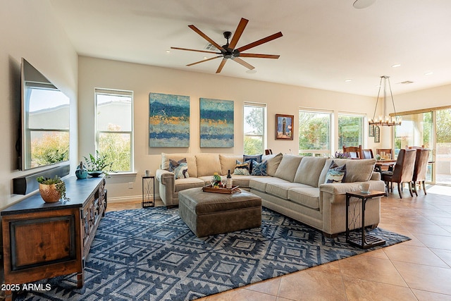 tiled living room with ceiling fan with notable chandelier