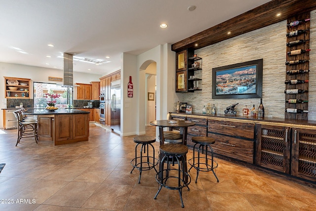 bar with backsplash, stainless steel appliances, and light tile patterned flooring