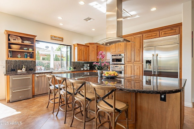 kitchen featuring dark stone countertops, decorative backsplash, stainless steel appliances, and a kitchen island