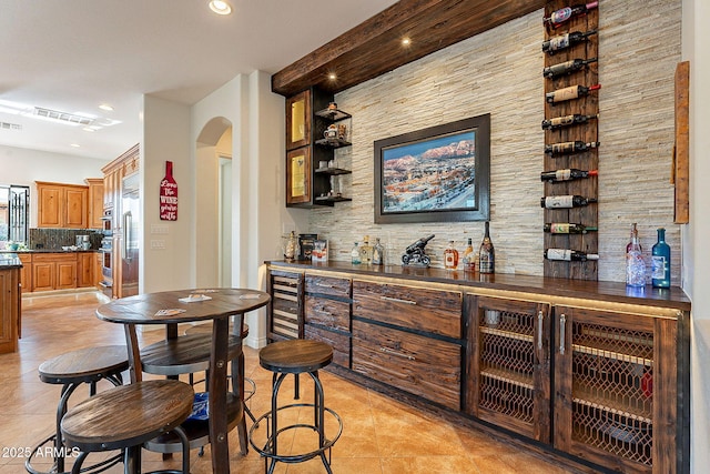 bar featuring tasteful backsplash, beverage cooler, and light tile patterned floors